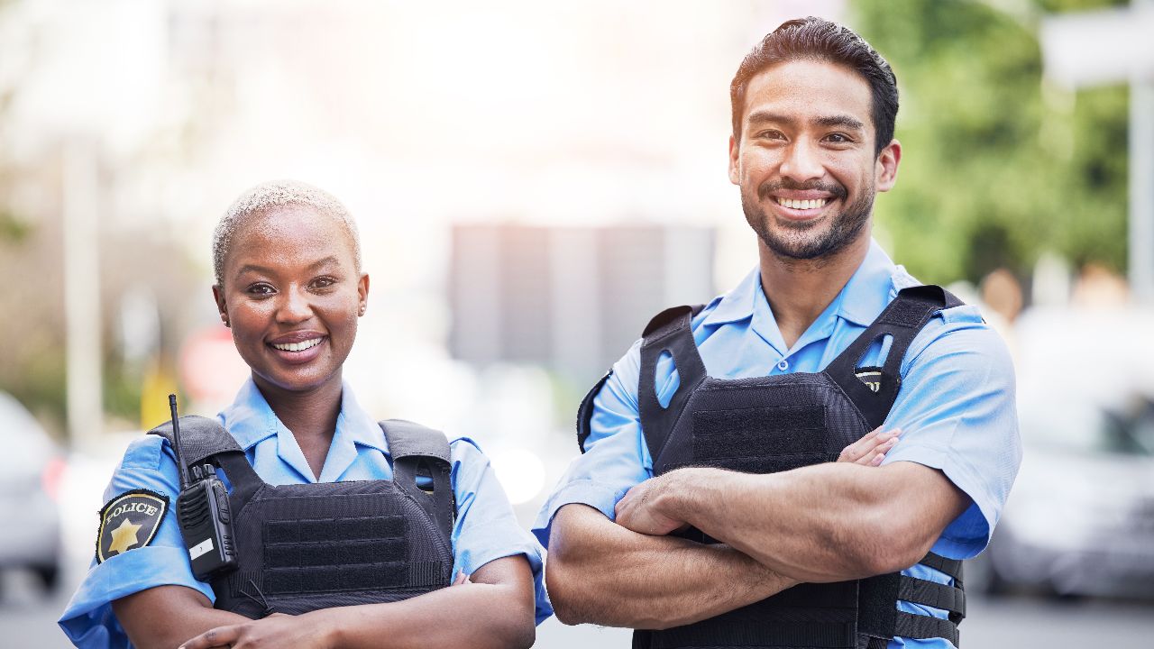 Happy, portrait and police with arms crossed in the city for security, safety and justice on the street